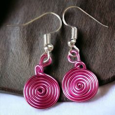 pair of pink earrings with spiral design on them