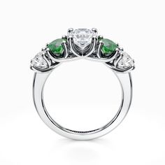 a three stone ring with green and white stones on the sides, set in 18k white gold