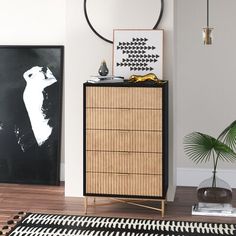 a black and white rug in a living room next to a wooden dresser with an abstract painting on it