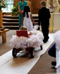 a small child in a toy car on the ground with other people standing behind it