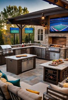 an outdoor kitchen with grill, seating and televisions on the wall above it at dusk