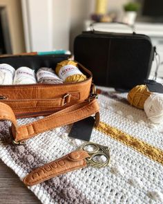 a crocheted blanket with scissors and yarn in the bag next to it on top of a table