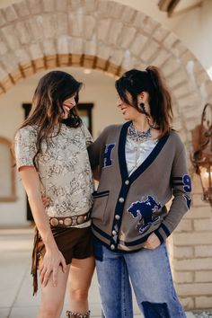 Inspired by the iconic bronc-riding Hay family, this preppy yet classic cardigan pays homage to the legacy of Lily’s husband and in-laws. Embellished with personal touches—like family initials, Lily’s birth year ‘97, and angel wings honoring her great-grandmother—it’s filled with history and heart. The striking blue accents add a bold contrast, making this heritage piece perfect for dressing up, whether you're in the arena or at the after-party. Chenille Patches Knitted Cardigan Little to Medium Collegiate Style Cardigan For Fall College Season, Collegiate Cardigan For College In Fall, Collegiate Style Fall Cardigan For College, Collegiate Fall Cardigan For College, Fall Collegiate Style College Cardigan, Fall Cardigan For College, Vintage Tops For College, Bronc Riding, Chenille Patches