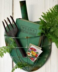 a garden tool and gardening utensils in a wire basket on a white wooden wall