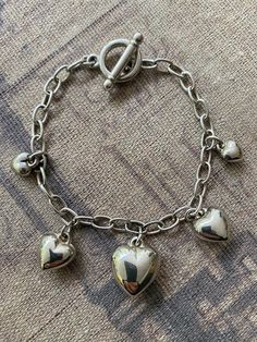 Puffy heart charms vintage silver-tone bracelet, very cute with graduated shiny heart charms and a toggle clasp with Korea stamp.  This item is used or estate and may have scratches and wear appropriate to it's age. I will do my best to describe anything I can see that is out of the ordinary. I consider photos as a part of the description. Silver Heart Charm Chain Bracelet, Silver Metal Chain Bracelet With Heart Charm, Vintage Silver Heart Charm Bracelet, Nickel-free Metal Charm Bracelet For Valentine's Day, Nickel-free Heart-shaped Metal Charm Bracelet, Metal Heart Bracelet With Toggle Clasp, Puffy Heart Charms, Puffy Heart, Toggle Clasp