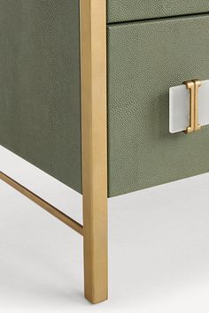 a close up of a green and gold dresser with two white knobs on it