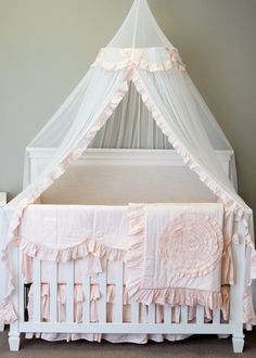 a white crib with pink ruffles and a canopy over the crib