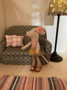 a stuffed mouse is standing in front of a couch