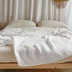 an unmade bed with white sheets and pillows