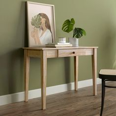 a wooden table with a plant on it next to a chair and a framed photograph