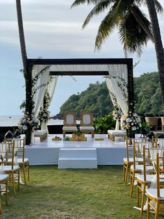 an outdoor ceremony set up with white linens and gold chairs, decorated with flowers