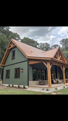 a large green house with a metal roof and wooden beams on it's side