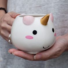 a person holding a white cup with a pink and gold unicorn face on the inside