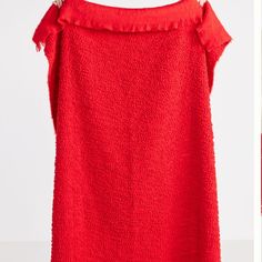 a red dress with ruffles on the shoulders is hanging from a hanger