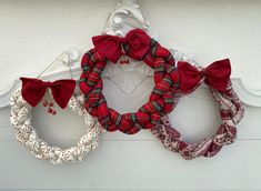 three red and white wreaths hanging from the side of a building with bows on them