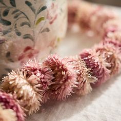 some pink flowers on a table next to a cup