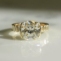 a yellow gold ring with an oval cut diamond in the center on a white surface