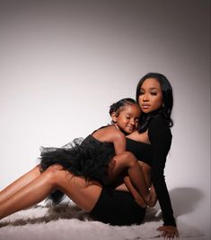 two women are posing for the camera with one holding another woman's back and she is wearing a black dress