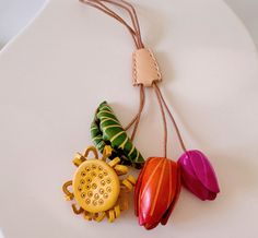 a white plate topped with three colorful flowers and a cell phone charm hanging from it's cord