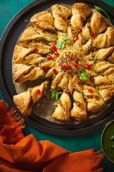 a platter filled with pastries on top of a green table next to sauces