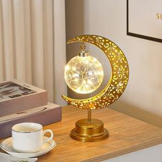 a lamp that is sitting on top of a table next to a cup and saucer