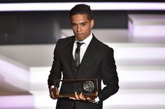 a man in a suit and tie holding an award