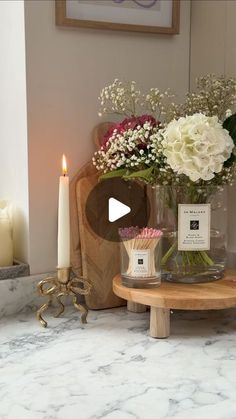 a table topped with flowers and candles next to a vase filled with white hydrangeas