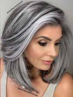 a woman with grey hair wearing a white tank top and silver highlights on her face