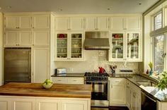 a large kitchen with white cabinets and wood counter tops on the island in front of an open window