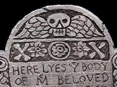 a grave marker with a skull on it's head and the words here lies body of m belved