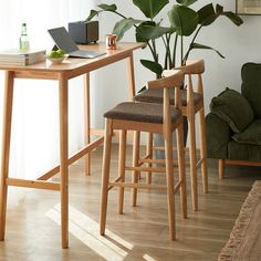 two wooden stools sitting next to a table with a laptop on it