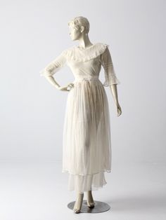 a mannequin wearing a white dress with ruffles on the neck and sleeves