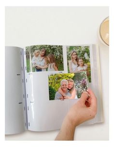 an open photo book with pictures of people and flowers on the pages, held in someone's hand