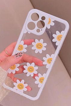 a woman's hand holding up a phone case with smiley face and flowers on it