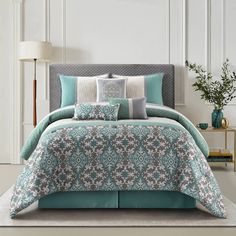 a bed with blue and white comforters in a room next to a lamp on a table