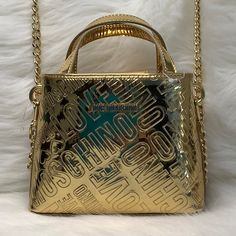 Nwot This Small Love Moschino Satchel Is Super Cute! For A Small Bag It Is Mighty In Fashion! Fits 6.5”Cell Phone At An Angle, Keys, Small Wallet, And A Few Accessories Comes In Gold Patent & Black Interior With Chain Link Strap. Convert From A Satchel To A Crossbody! New, Excellent Condition! Features: Love Moschino Color Gold Signature Logo Strap Length 52 Inches Drop 25” Interior Black Signature Lining Gold Logo Lettering Gold-Tone Hardware Concealed Magnetic Closure Double Circular Top Handle Detachable Shoulder Strap Internal Slip Pocket Partitioned Compartment Measures 9"H X 7.5”W X 2.5”D Measures Without Handles, 5.7/8” Clean With Damp Cloth Retails For $350 Asking $2 Gold Shoulder Bag With Logo Hardware For Shopping, Gold Tote Bag With Logo Hardware, Gold Shoulder Bag With Logo For Shopping, Gold Logo Shoulder Bag For Shopping, Party Shoulder Bag With Logo Hardware, Gold Evening Bag With Logo, Designer Bags With Logo Hardware For Party, Designer Party Bag With Logo Hardware, Love Moschino