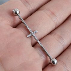 a person is holding a cross shaped nose ring