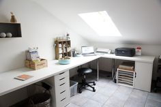 a white desk sitting under a skylight in a room with lots of drawers and shelves