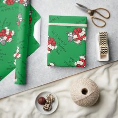 a green wrapping paper with santa clause on it next to scissors and other craft supplies