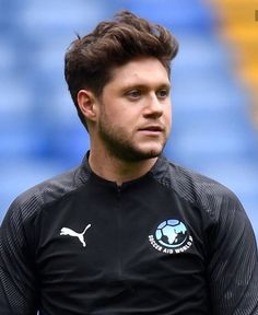 a man in black shirt standing on a soccer field