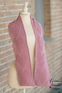 a pink knitted shawl sitting on top of a mannequin