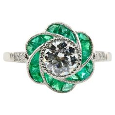 a diamond and emerald flower ring on a white background