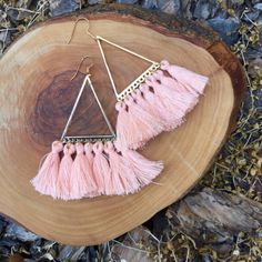 two pink tasselled earrings sitting on top of a piece of wood