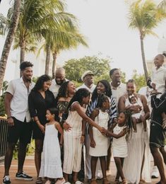 a group of people standing next to each other in front of trees and palm trees