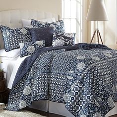 blue and white comforter set with flower design on the bed in front of window