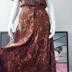 Autumn Palette Challis. 1980's J. Christopher Skirt. Spice tone paisley, with swirls of turquoise, plum, gray, sangria. Four button yoke, full silhouette. Graceful cascade from band waist to hem. Ideal with boots, any heel. About mid-calf. Four pearl buttons at the inset waist. Pleats are asymmetrical, from the left side to back. The challis is tailored, sturdy, and smooth surfaced. Hem sweep is 80 inches all around. Made in USA. Labeled size 8.  Useful measurements below. VINTAGE  26-28" Waist  48" Hip 34-1/2" Length Vintage Brown Skirt With Buttons, Vintage Full Skirt Bottoms With Buttons, Vintage Full Skirt With Buttons, Vintage Fall Skirt With Buttons, Vintage Skirt For Fall, Retro Brown Skirt With Button Closure, Vintage Skirt With Button Closure, Vintage Skirt Bottoms With Button Closure, Vintage Skirt Bottoms With Buttons