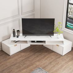 a flat screen tv sitting on top of a white entertainment center next to a window