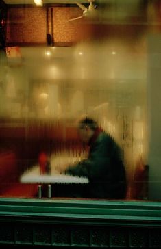 a blurry photo of a man sitting at a table in front of a window