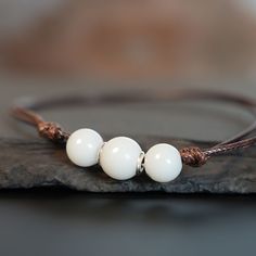 "Breastmilk pearl beaded bracelet with 1mm brown waxed cord.  Our  Simple Pearl Beads Bracelet is a pure and simple celebration of the natural beauty of motherhood. Sterling silver core in the central bead (rose or yellow gold options available). Add pearl powder for lustrous effect.  For all our breast milk bracelet collection, please visit: https://www.etsy.com/ca/shop/KeepsakeMom?ref=seller-platform-mcnav&section_id=27169694 For all breastmilk jewelry, please visit:  https://www.etsy.com/ca/s Breast Milk Jewelry Bracelet, Pearl Beaded Bracelet, Breastmilk Jewelry, Silver Core, Simple Pearl, Pearl Powder, Jewelry Pearl, Bracelet Collection, Beads Bracelet