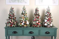 three christmas trees are sitting on top of a green table